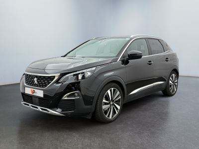 La voiture grise est garée dans une grande pièce au sol noir.