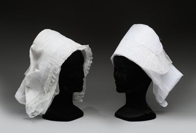 deux têtes de mannequins noires coiffées de chapeaux blancs à volants blancs