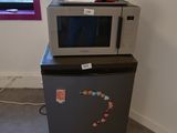 un micro-ondes posé sur un réfrigérateur dans une pièce