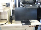 a computer monitor sitting on a desk next to a microwave