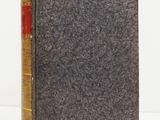 an old book sitting on top of a white table next to a white wall