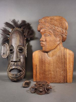 Deux masques en bois sculptés sont posés l'un à côté de l'autre sur une table
