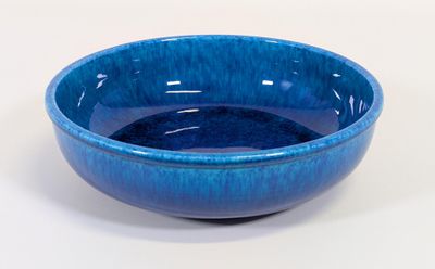 un bol bleu posé sur une surface blanche, sur fond blanc