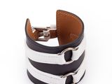 un gros plan sur un bracelet en cuir noir et blanc muni d'un fermoir en métal