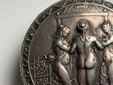a silver plate with a picture of three women on it