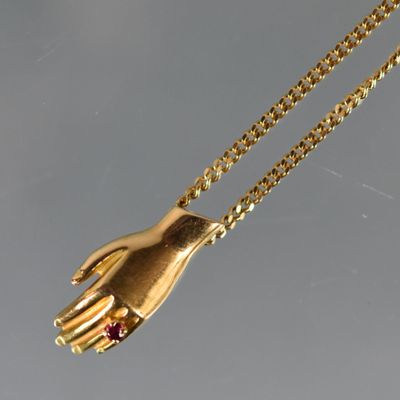 un gros plan sur un collier en or avec une main accrochée à une chaîne