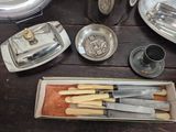 a tray with knives and other silverware on a wooden table