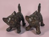 une paire de figurines de chats en bronze sur fond rose