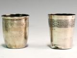 two silver cups with designs on them sitting side by side