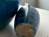 a blue vase sitting next to a blue vase on a table