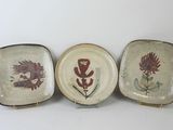 three plates with different designs on them sitting on a white surface