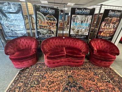 trois canapés en velours rouge et un tapis dans un magasin