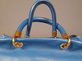blue leather handbag with gold handles on a wooden table