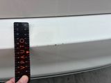 a person holding a ruler in front of a white car