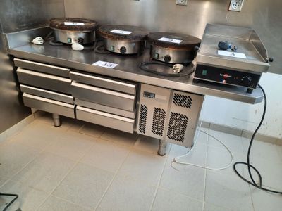 une cuisinière sur laquelle sont posées trois casseroles, dans une cuisine