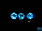 three blue topaz gems in a row against a black background