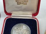 a silver medal in a red case with a blue ribbon