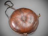 an old leather purse with a metal handle on a gray surface