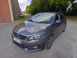 La voiture grise est garée sur le parking, à côté d'un immeuble.