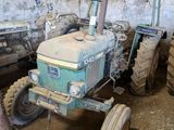 un tracteur qui est à l'abandon dans la boue, dans une grange