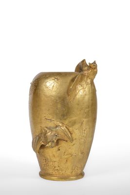 a gold vase with a bird on it on a white surface