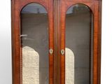 an antique wooden display cabinet with two glass doors