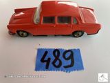 une petite voiture rouge posée à côté d'une feuille de papier bleue