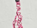 a pink sculpture on a white pedestal with a black top