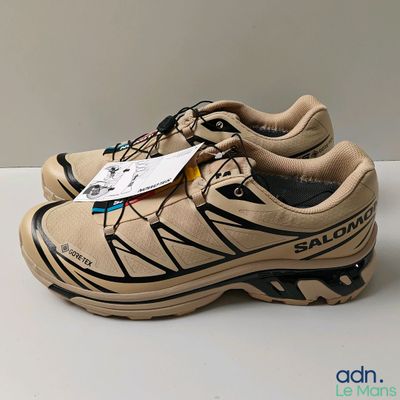 the shoe is tan and black with a tag on it