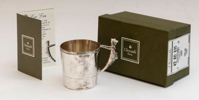 une tasse en argent posée à côté d'une boîte de thé