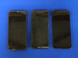 trois iPhones noirs posés côte à côte sur une surface bleue