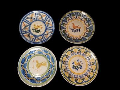 quatre assiettes ornées de motifs d'oiseaux et de fleurs sur fond noir