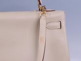 the handle of a beige handbag with a gold clasp