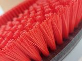 a close up of a red brush on a white surface
