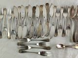 a lot of forks and spoons laid out on a table
