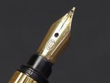 close up of a fountain pen with a gold nib on a black background