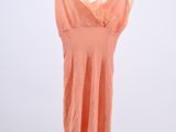an orange dress hanging on a black hanger on a white wall