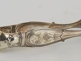 an antique silver plated spoon and spoon rest on a white surface