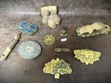 Plusieurs objets anciens en laiton sont posés sur une table, à côté d'une pièce de monnaie