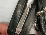 a hand holding a black purse with a zipper open
