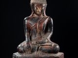 une statue représentant une personne assise sur un rocher, sur fond noir
