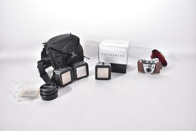 a camera, a camera case, and other items on a white surface