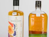 Deux bouteilles d'alcool sont posées l'une à côté de l'autre sur une surface blanche.