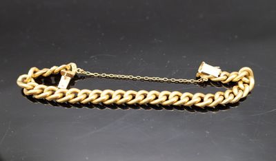 gros plan d'un bracelet en chaîne en or sur une surface noire