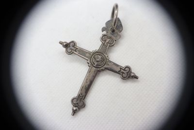 a silver cross on a white surface with a black background
