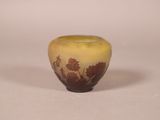 a small yellow vase with a brown design on it