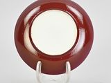 a red and white plate with a white center on a stand