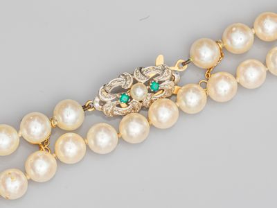 un gros plan sur un collier orné de perles et d'émeraudes