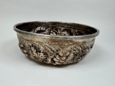 un bol en argent posé sur une table blanche, sur fond blanc