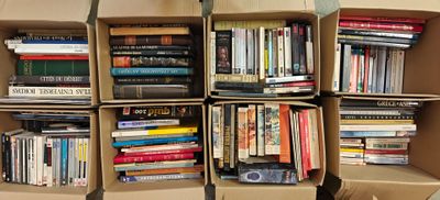 de nombreux livres rangés dans des cartons empilés les uns sur les autres